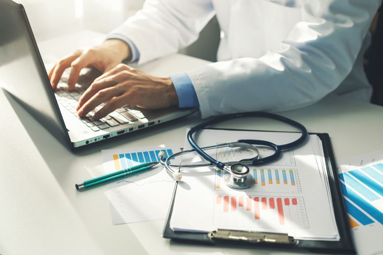 doctor working on computer charts stethoscope