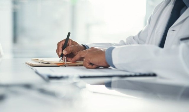 Doctor writing on medical document forms