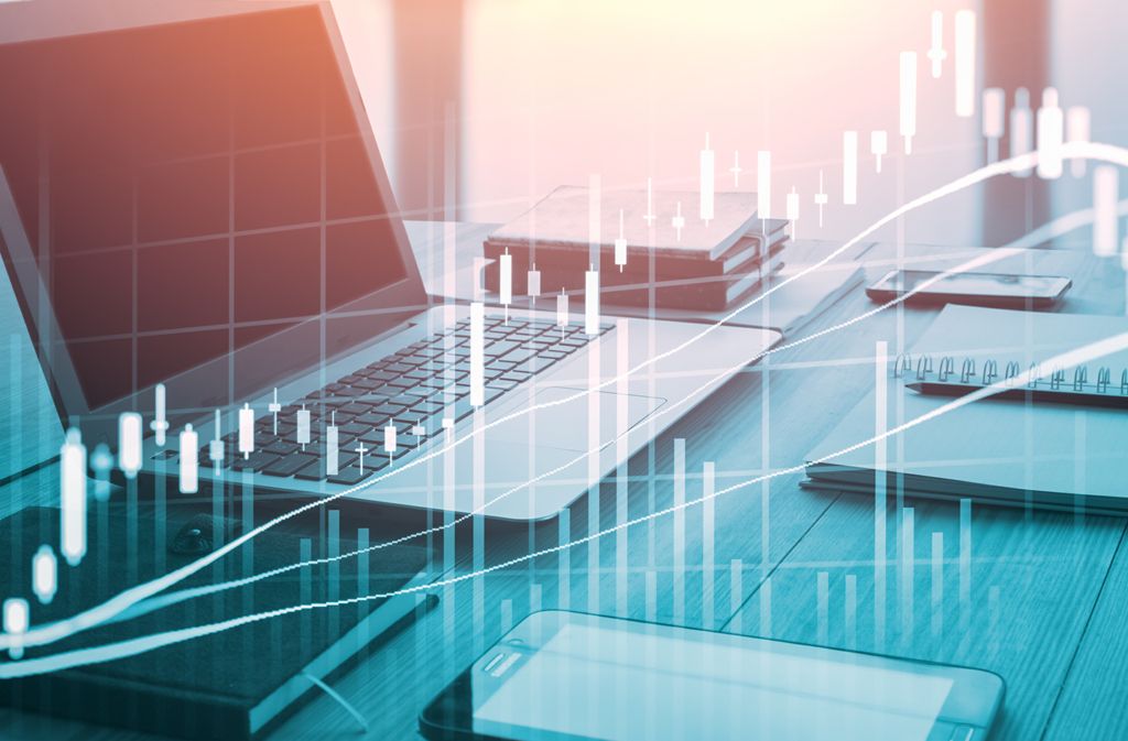 Computer on desk with financial data visuals displayed