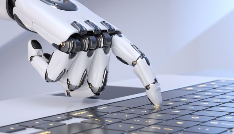 GettyImages-1356162320_compressed White robot cyborg hand pressing a keyboard on a laptop