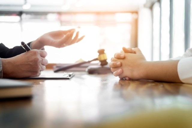 Hands on a table with gavel in the background representing mediation from Woodruff Sawyer.