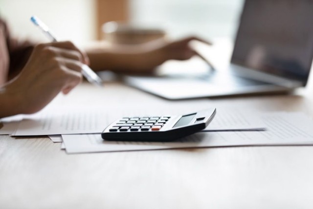 person writing calculator laptop