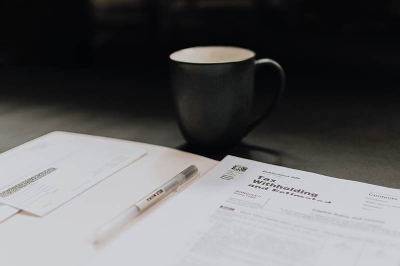 IRS Forms, Coffee Mug, and Pen on a table.
